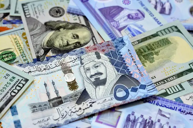 Pile of American dollar bills American cash money banknotes with Saudi Arabia riyals money banknotes. Image used for illustrative purpose