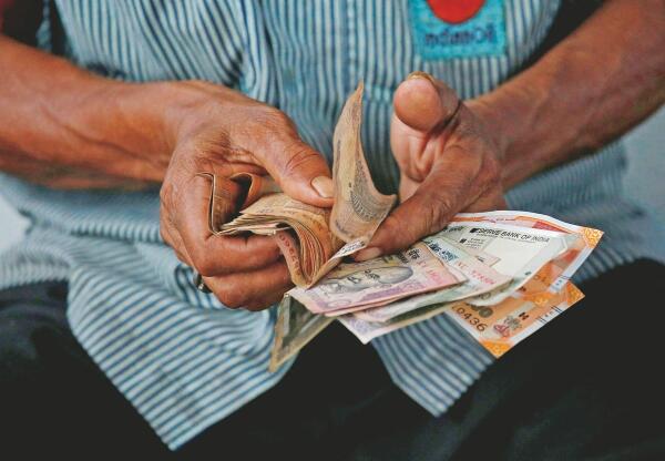 An attendant at a fuel station arranges Indian rupee notes in Kolkata